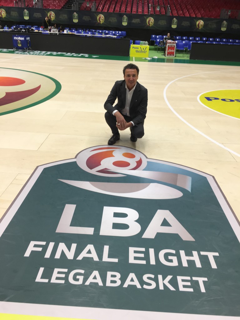 Patron Dalla Riva posa sulla sua ultima creazione accanto al logo di Legabasket organizzatrice della Final Eight 2017 di Rimini Fiera